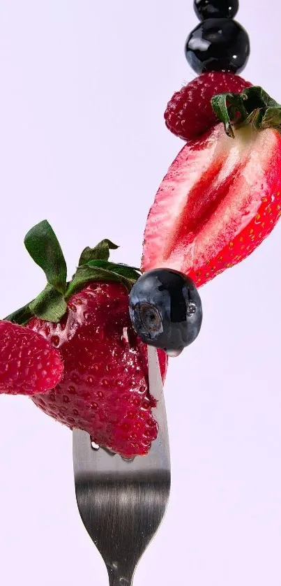 Vibrant display of berries on a fork set against a light pink background.