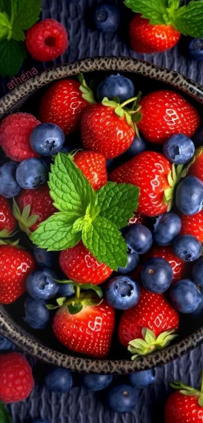 A vibrant bowl of strawberries and blueberries garnished with mint leaves.