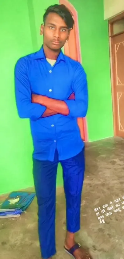 Young man in blue with a green background, showcasing vibrant fashion style.