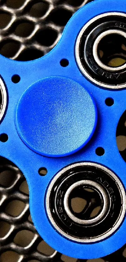 Vibrant blue fidget spinner on a mesh background.