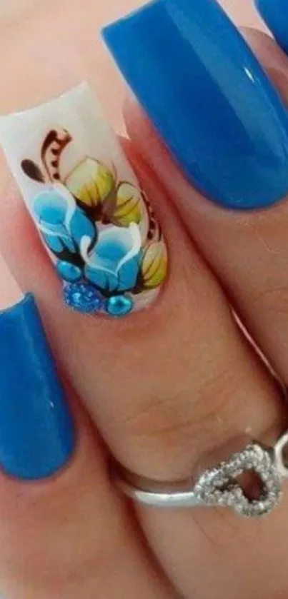 Vibrant blue nail art with floral design on a woman's finger.