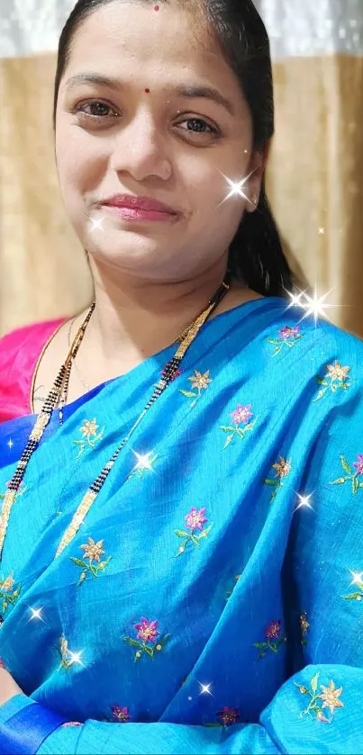 Woman in vibrant blue saree with floral design.