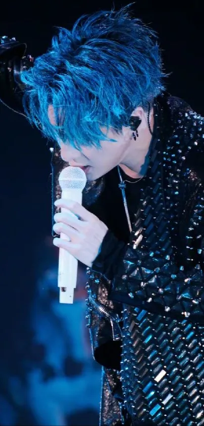 Singer with vibrant blue hair performing on stage, holding a microphone.