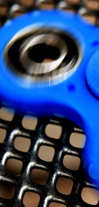 Vibrant blue fidget spinner on metallic grid background.