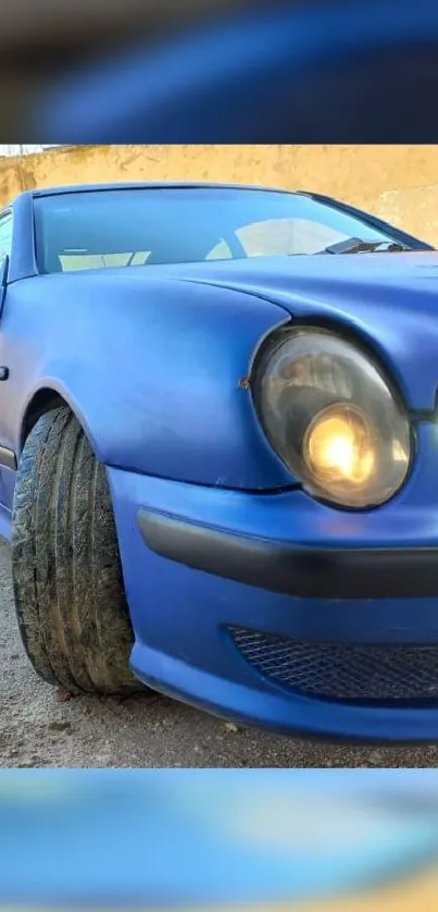 Sleek blue sporty car with glowing headlights.