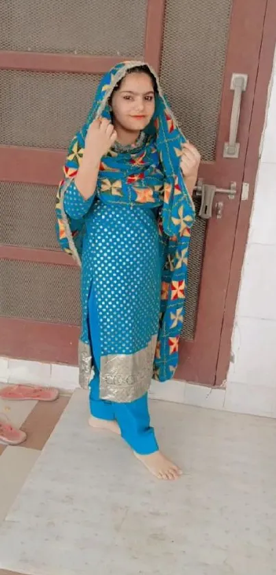 Woman in vibrant blue traditional outfit with patterns.