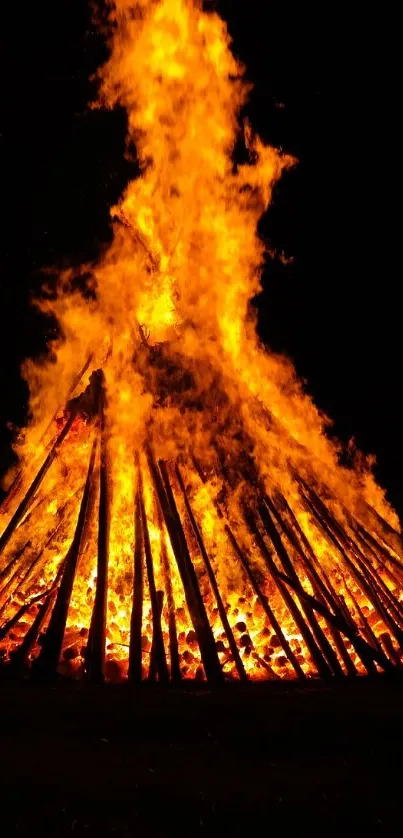 Bonfire burning brightly against dark night backdrop.