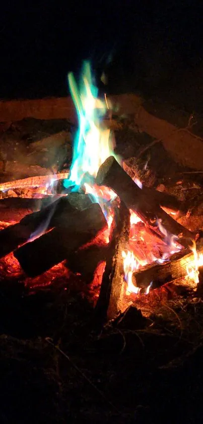 Vibrant campfire with blue flames on a dark night background.