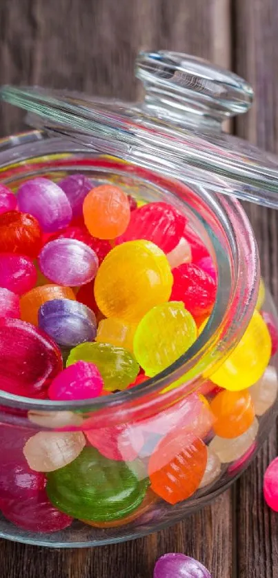 Glass jar filled with vibrant, colorful candies on wooden background.