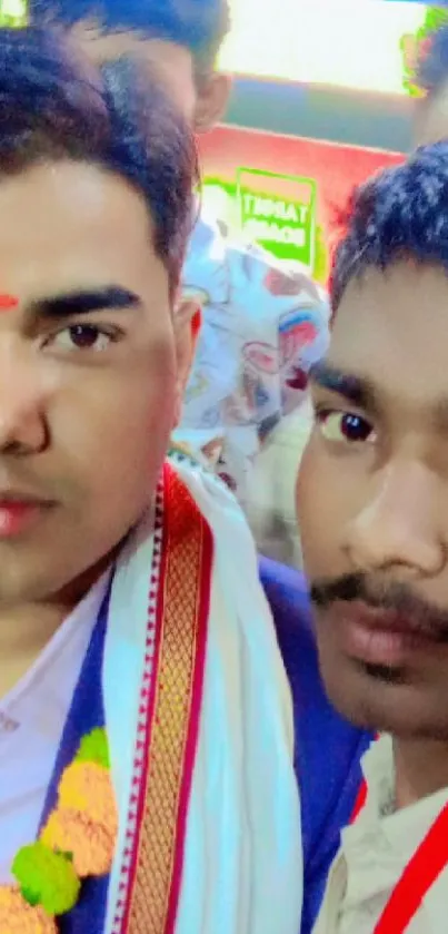 Two individuals smiling at a celebration event in vibrant attire.