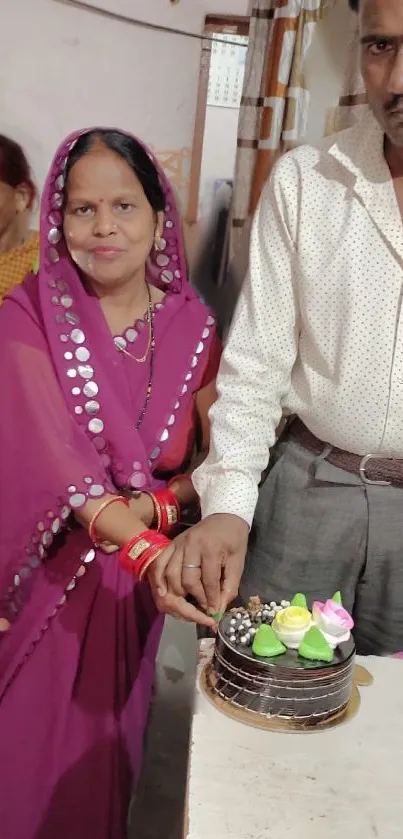 Couple celebrating with a cake, wearing traditional attire.