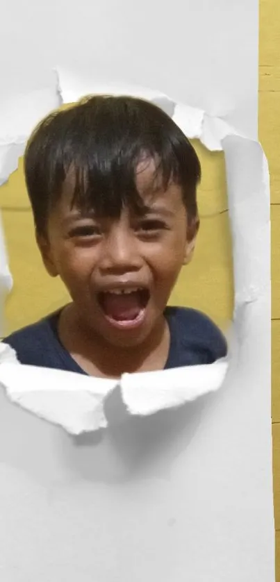 Child expressing joy through torn paper on yellow themed wallpaper.