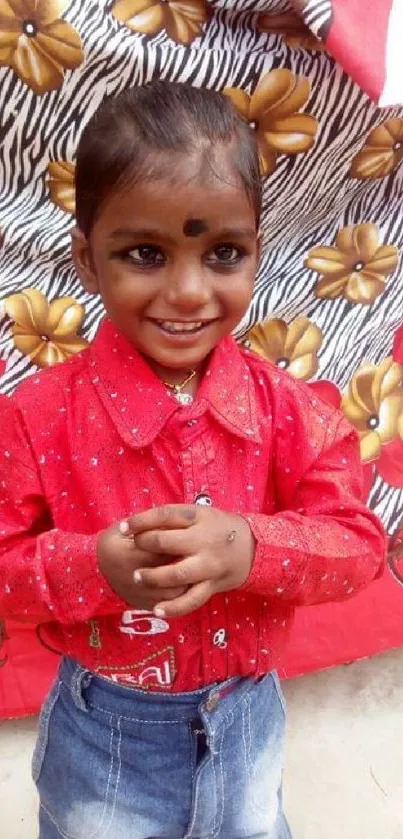 Joyful child in red shirt with floral background.