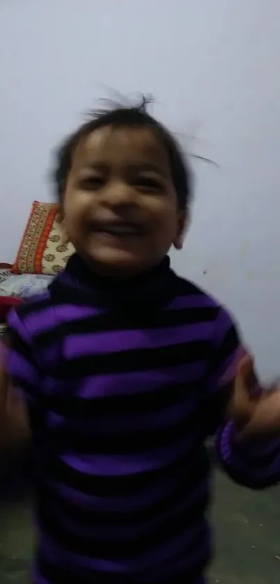 Cheerful child in a striped sweater against a cozy room backdrop.