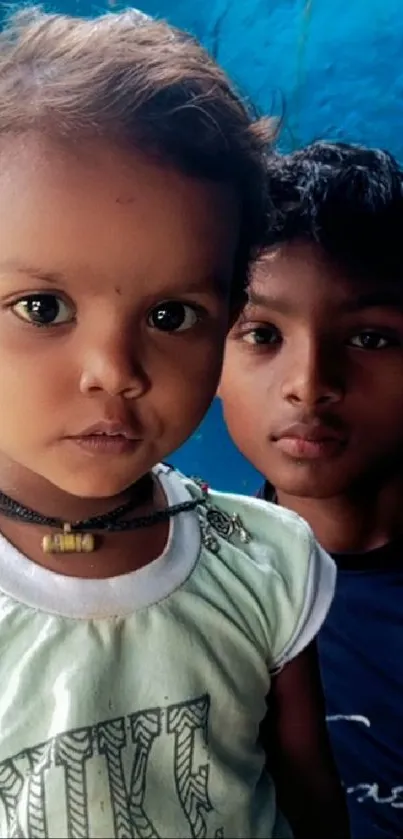 Portrait of two children with blue backdrop.