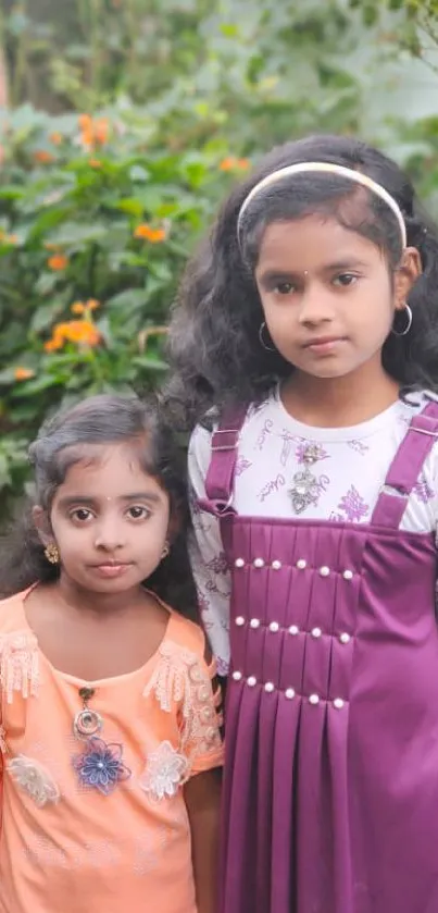 Two young girls in colorful dresses standing in a lush green garden.