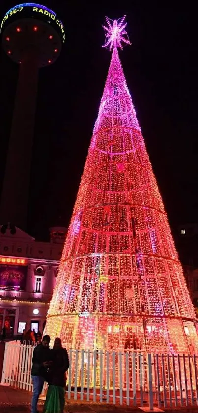 Vibrant Christmas tree illuminated with colorful lights at night.