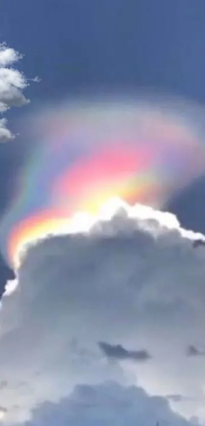 A rainbow emerges from clouds against a serene blue sky.