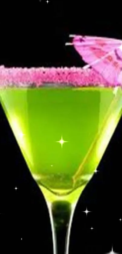 Green cocktail with pink umbrella on black background.