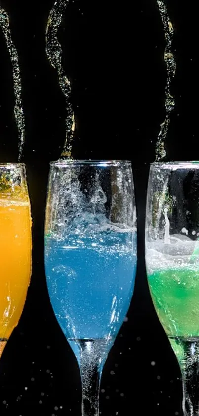 Three glasses with colorful liquids splashing on black background.