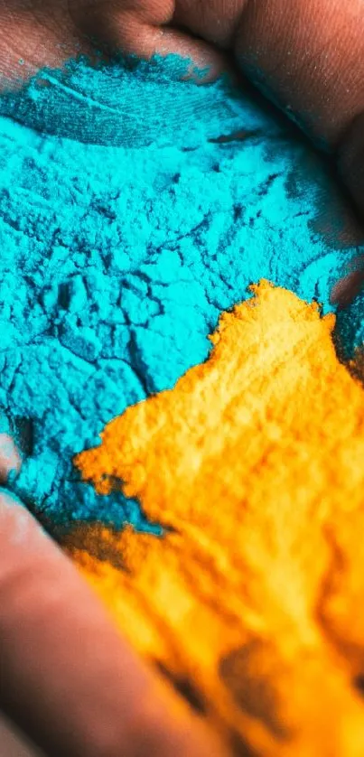 Hand with vibrant blue and orange powders creating colorful art.
