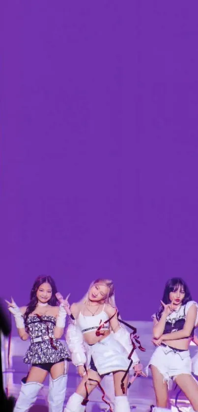 Girl group performing on stage with a vibrant purple background.