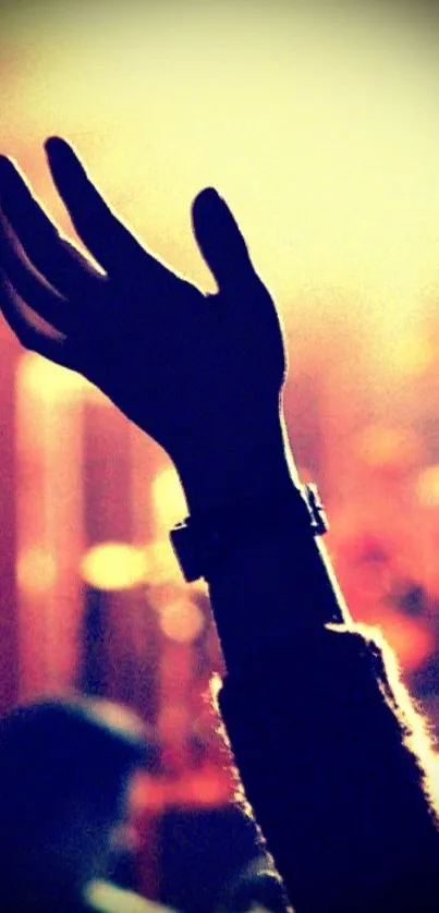 Silhouette of a raised hand at a vibrant concert with colorful lighting.