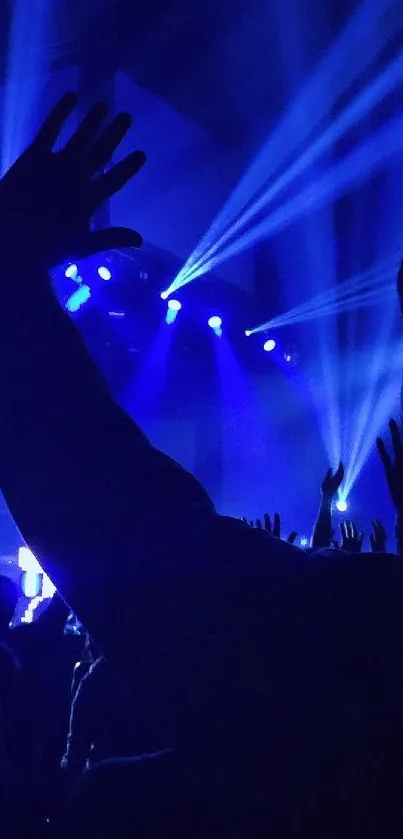 Hands raised in a concert setting with blue stage lights.