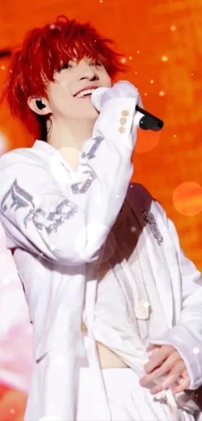 Performer with red hair in white outfit on orange stage.