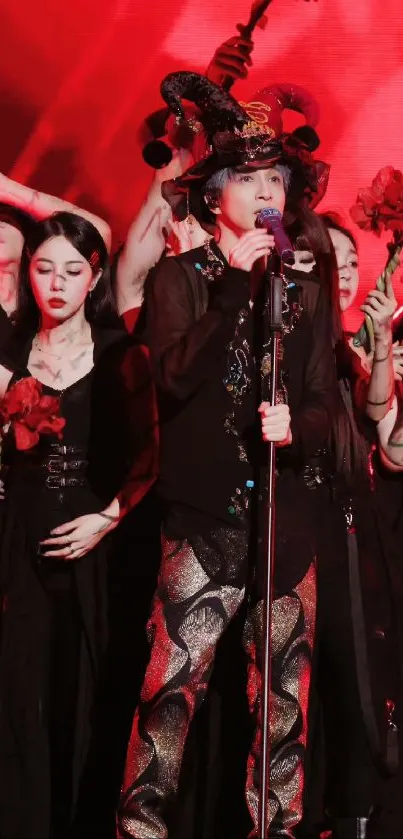 Singer performs on stage with vibrant red backdrop and dancers holding flowers.