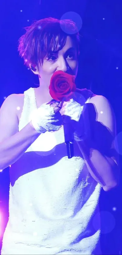 Performer at concert holding red rose under purple lights.