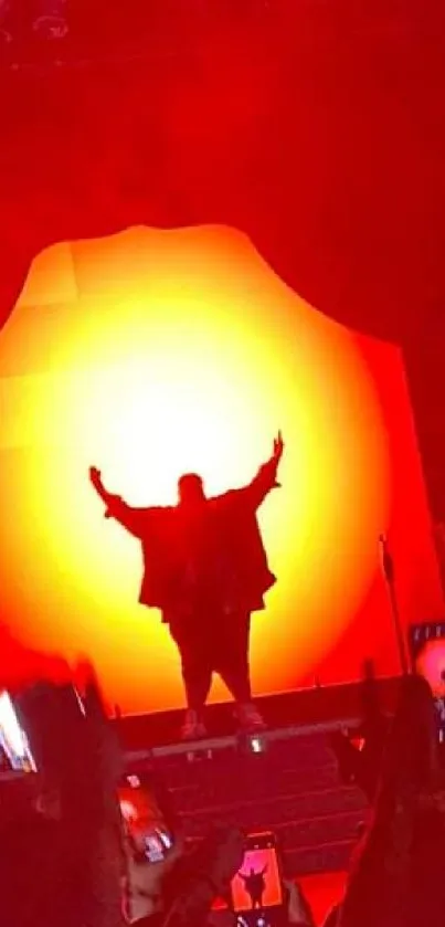 Silhouette of performer at a live concert with bright red and yellow lighting.