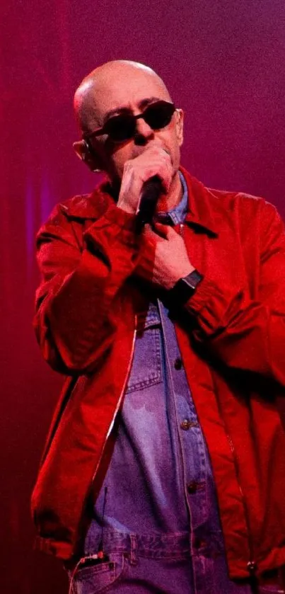 Performer in red jacket singing under vibrant stage lights.