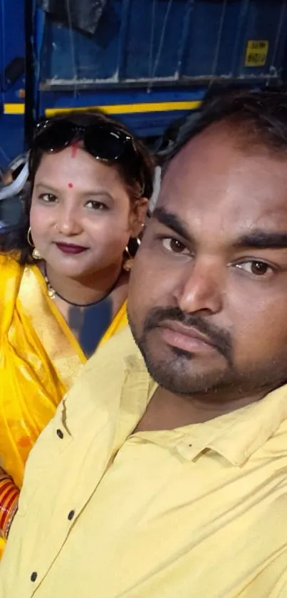 Vibrant couple in yellow attire, smiling warmly.