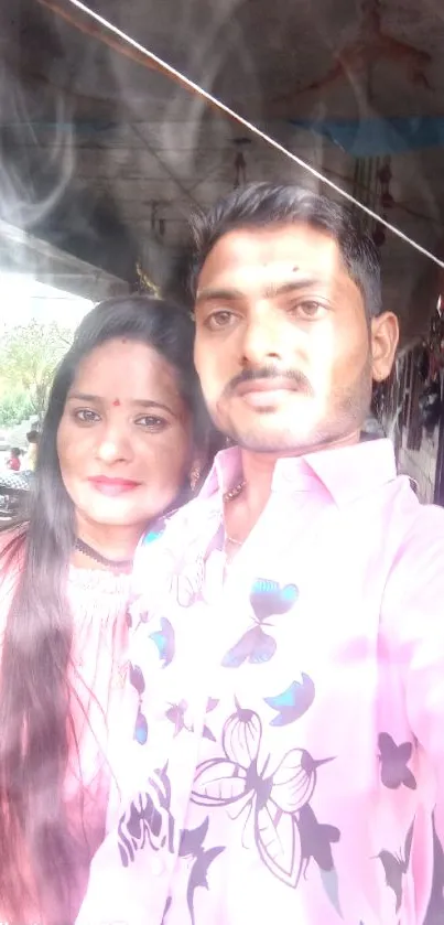 Couple in vibrant pink and blue attire in a rustic setting with natural light.