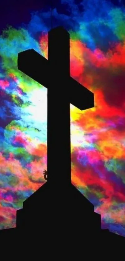 Cross silhouette with vibrant rainbow sky in the background.