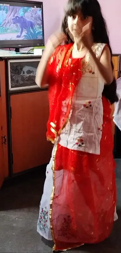 Girl in vibrant red traditional attire indoors.