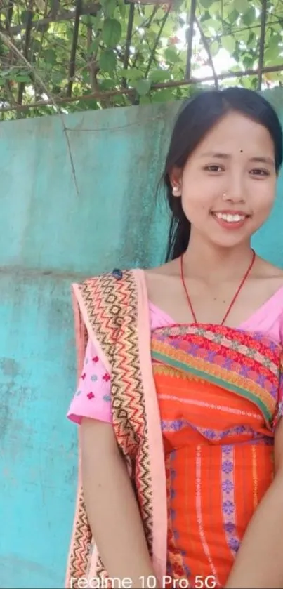 Woman in colorful traditional attire with a teal background.