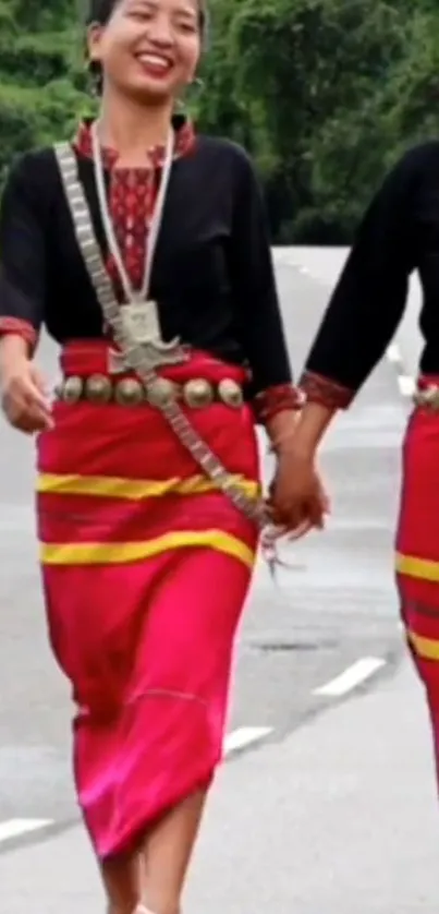 Two people in traditional clothing holding hands on a road.