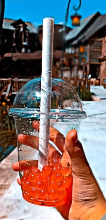 Hand holding bubble tea under vibrant blue sky.