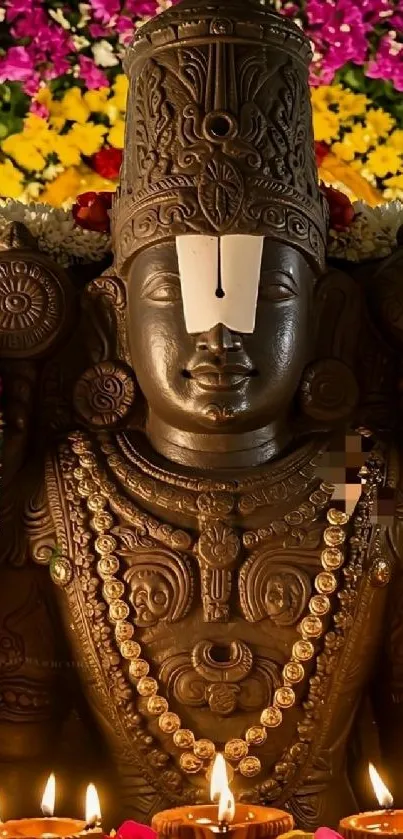 Intricately designed deity surrounded by colorful flowers and candles.