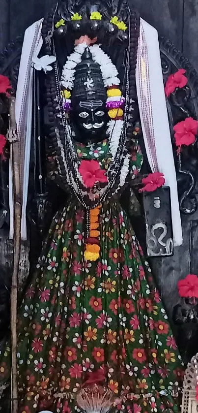 Divine idol adorned with flowers and traditional attire in a serene setting.