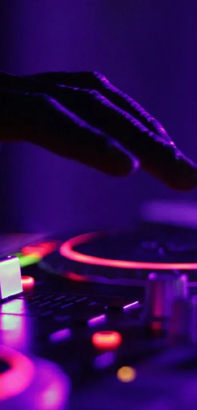 DJ hand on mixer with neon purple and red lights.