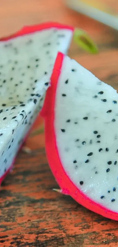 Dragon fruit slice with vibrant pink peel on wooden surface.