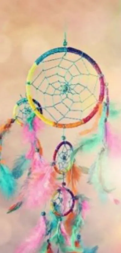 Colorful dreamcatcher with feathers on a soft peach background.