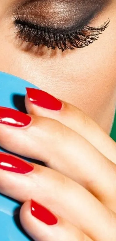 Close-up of vibrant red nails clutching a blue cup.