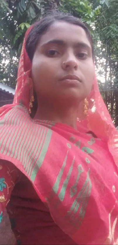 Woman in vibrant red saree with green patterns.