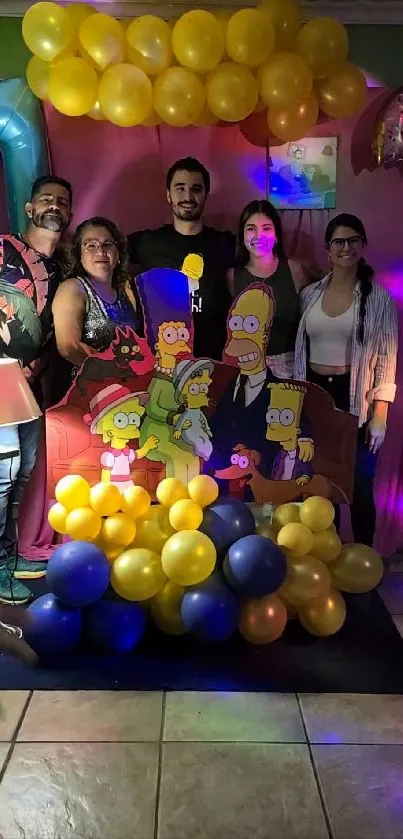 People posing with colorful balloons and cartoon cutouts at a festive event.