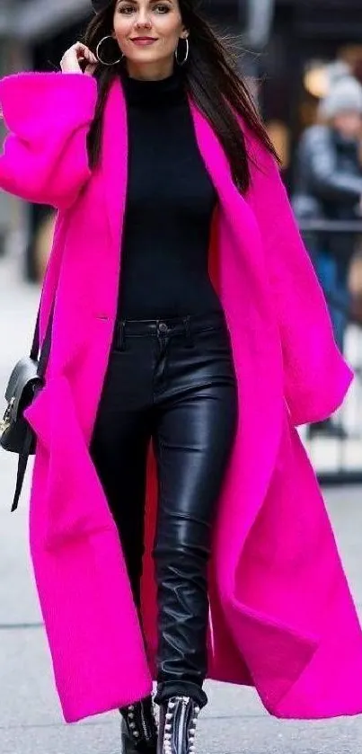 Fashionable woman in a vibrant pink coat and black ensemble on the street.