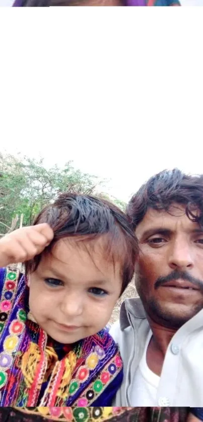 Father and child in colorful attire with natural backdrop.